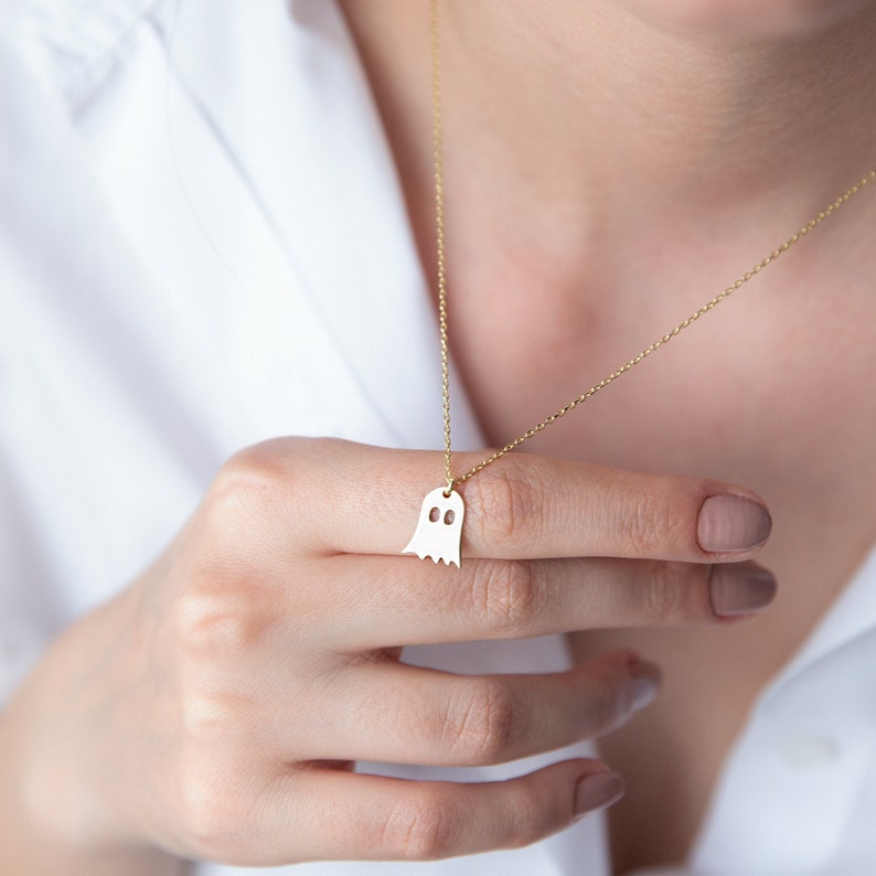 A gold chain necklace with a ghost-shaped pendant
