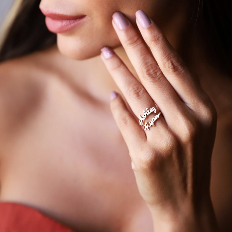 A silver ring with the names 'Ashley' and 'Ryan' engraved on it.