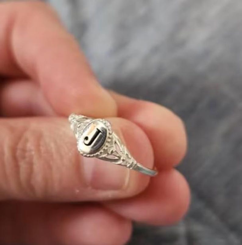 A 925 sterling silver ring with an oval-shaped setting featuring the letter 'K' in black lettering.