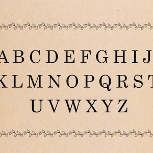 A black and white alphabet on a brown background with a vine border. The alphabet is in uppercase letters and is centered on the page. The letters are spaced evenly apart. The vine border is made up of small leaves and is located at the top and bottom of the page.