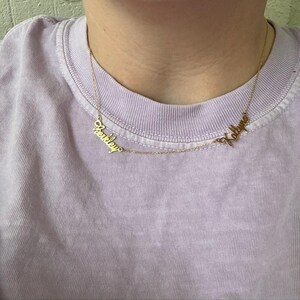 A gold necklace with two names on it.