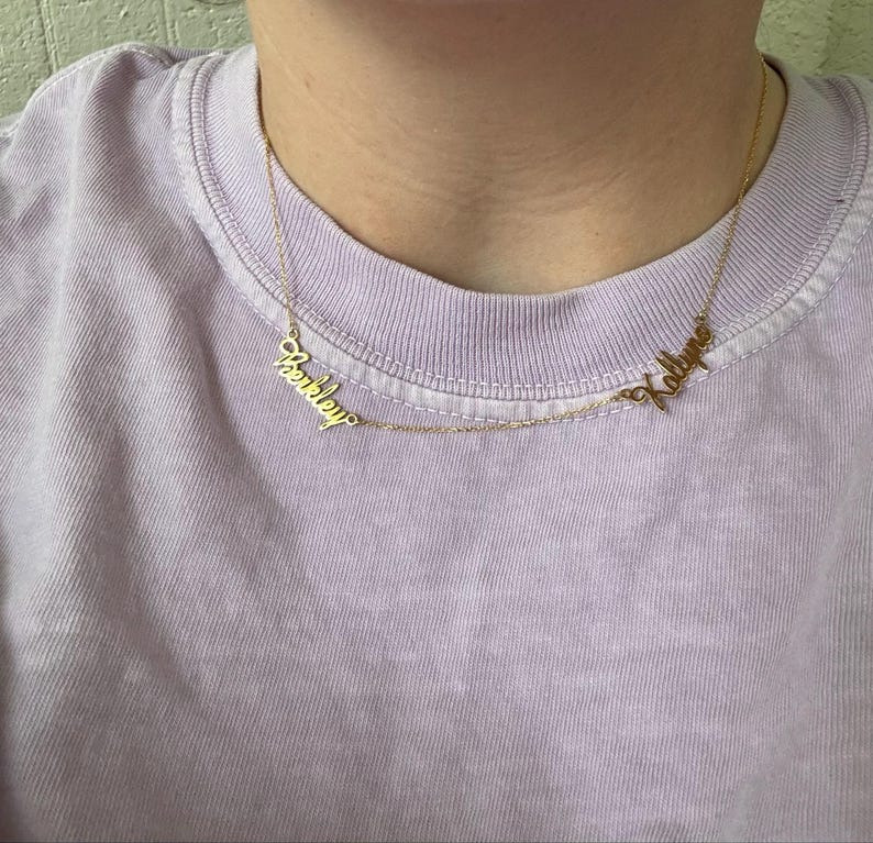 A gold necklace with two names on it.
