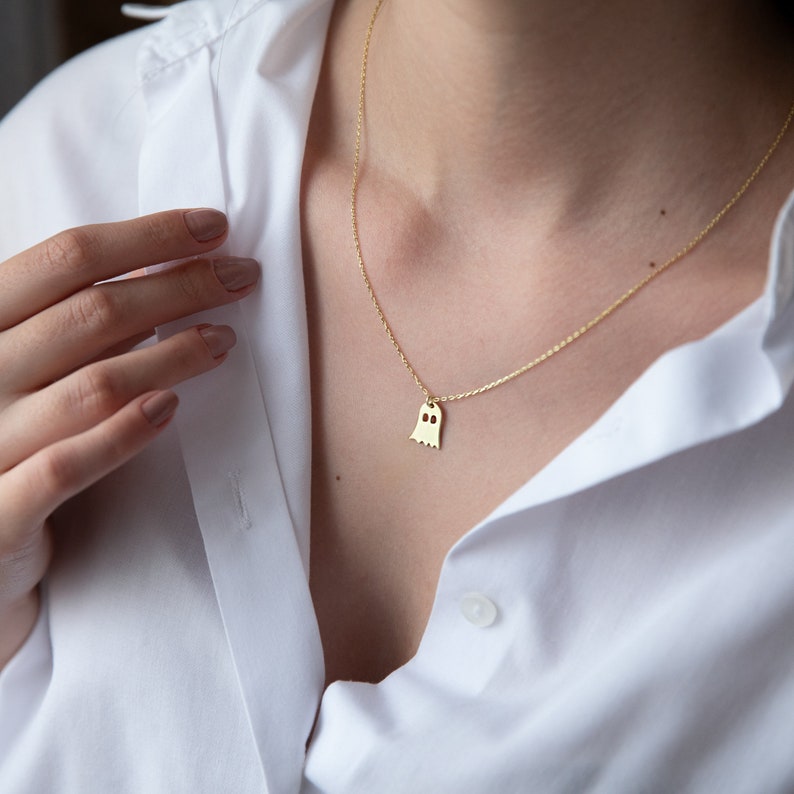 A gold chain necklace with a ghost-shaped pendant