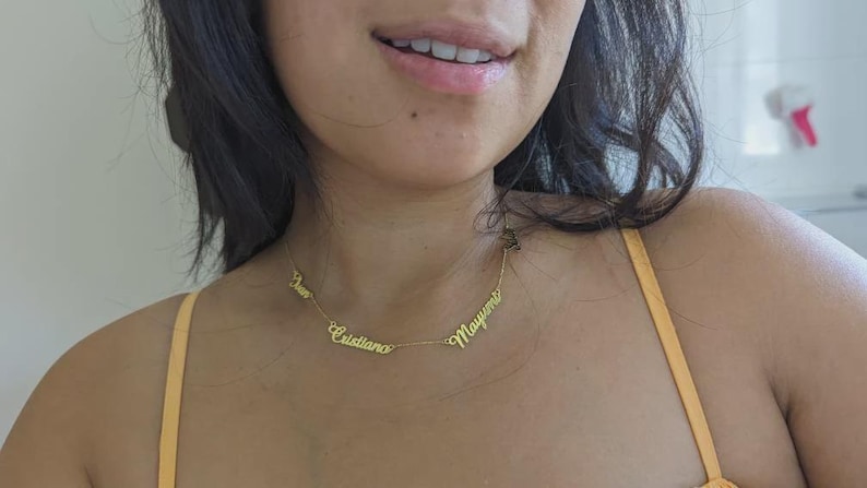 A gold necklace with three names on it.
