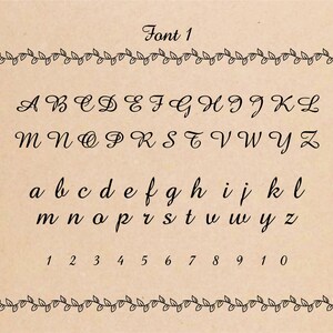 Font 1 in black cursive script on a brown background with a vine border. The alphabet is shown in uppercase and lowercase letters, followed by the numbers 1 through 10.