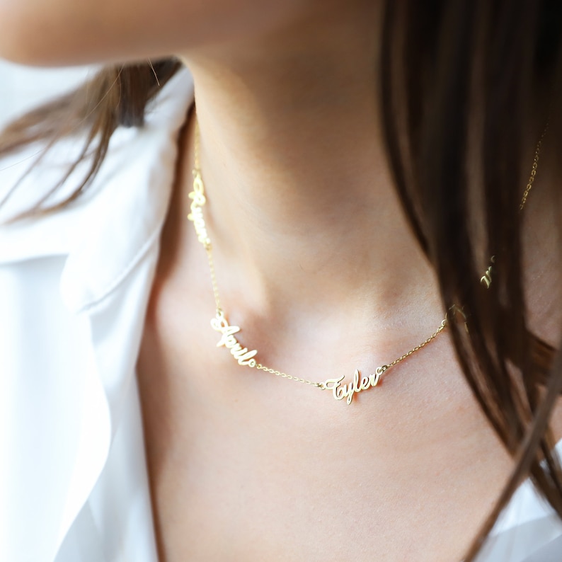 A gold chain necklace with three names, 'Apollo', 'Tyler', and 'Brynn', spelled out in cursive script.