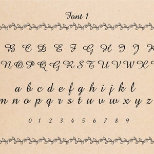 Font 1 in black script font on a tan background. The alphabet is displayed in uppercase and lowercase letters. Numbers 0 through 9 are also displayed.