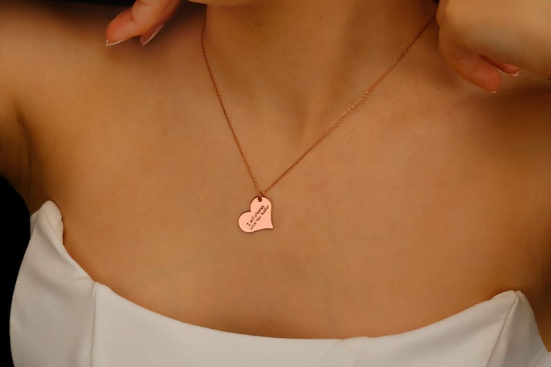 A rose gold heart-shaped pendant necklace with the inscription 'I am strong, like the sea'.