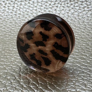 May include: A brown and black leopard print glass ear gauge plug.