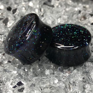 May include: Pair of black ear gauges with iridescent glitter embedded in the resin.