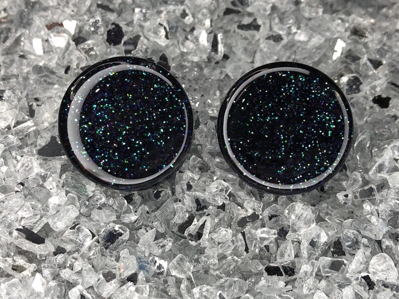 May include: Two black round glass cabochons with iridescent glitter embedded in the glass.