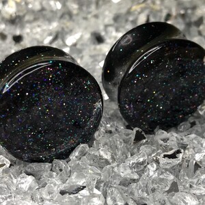 May include: Pair of black ear gauges with iridescent glitter embedded in the resin.