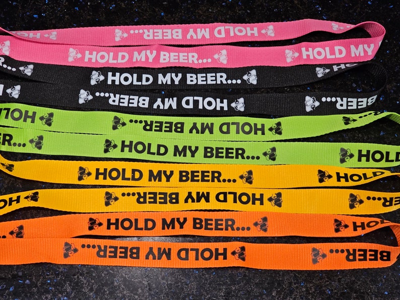 K&ouml;nnte beinhalten: Ein Set aus sechs bunten Lanyards mit dem Aufdruck "Hold My Beer..." Die Lanyards sind in Pink, Schwarz, Gr&uuml;n, Gelb und Orange.