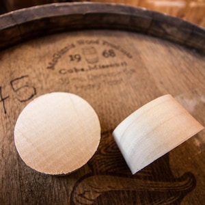 May include: Two wooden circles, one flat and one slightly curved, are sitting on top of a wooden barrel. The barrel has a label that reads "1968" and "Coca-Cola, Minnesota".