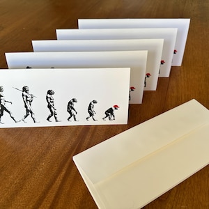 Könnte beinhalten: Ein Set weißer rechteckiger Umschläge mit einer schwarzen grafischen Darstellung der menschlichen Evolution. Das Design zeigt die Entwicklung vom aufrechten Menschen bis hin zu einer gebeugten Figur mit einer leuchtend roten Baseballkappe.