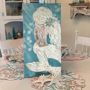 Mermaid painting an old barn board.