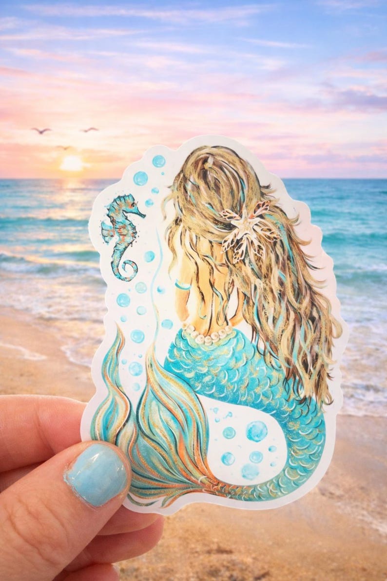 Peut inclure: Un autocollant repr&eacute;sentant une sir&egrave;ne aux longs cheveux blonds et &agrave; la queue turquoise, vue de dos. Un hippocampe et des bulles sont &eacute;galement repr&eacute;sent&eacute;s. L'arri&egrave;re-plan est une sc&egrave;ne de plage avec un coucher de soleil.