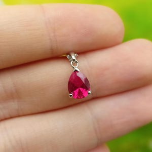 May include: A teardrop-shaped pendant with a bright red gemstone set in silver.