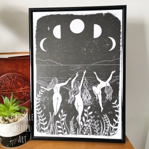 May include: Black and white print of three women dancing in a circle around a bonfire on a beach with a crescent moon and full moon in the sky.