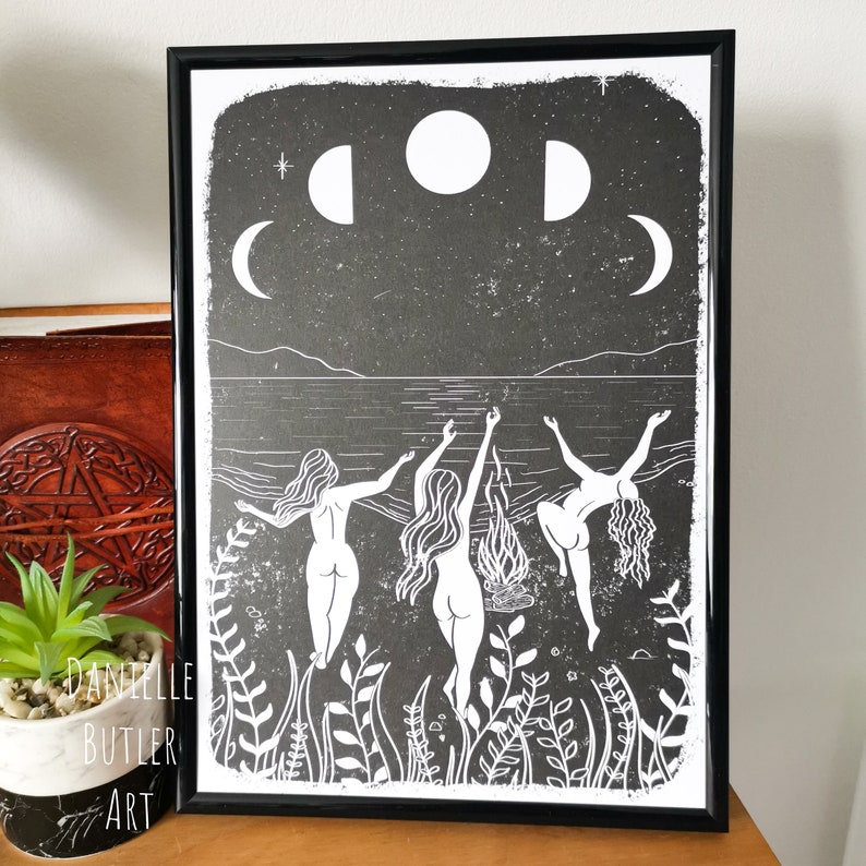 May include: Black and white print of three women dancing in a circle around a bonfire on a beach with a crescent moon and full moon in the sky.