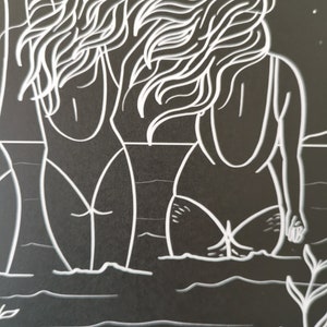 Op de afbeelding: Een zwart-witte lijntekening van twee vrouwen met lang haar die in het water staan. De vrouwen dragen badpakken en kijken weg van de kijker. De tekening is op een zwarte achtergrond.