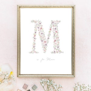May include: A framed print with a watercolor illustration of the letter M made of pink and purple flowers. The text "M is for Mara" is written below the letter.