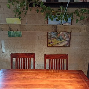 Puede incluir: Una mesa de comedor de madera con dos sillas. La mesa es de madera oscura y tiene un acabado natural. Las sillas también son de madera y tienen un acabado marrón claro. Una lámpara de madera cuelga sobre la mesa.