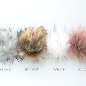 May include: Four faux fur pom poms in different colors: gray, brown, white, and blush.