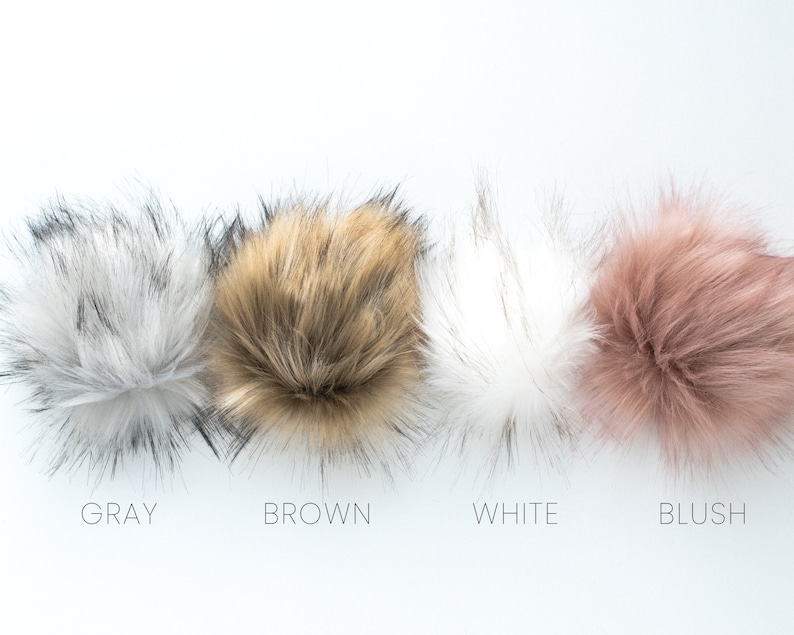 May include: Four faux fur pom poms in different colors: gray, brown, white, and blush.