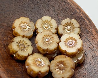 Eight Czech glass hibiscus flower beads in opaque caramel with picasso finish resting in a wooden bowl.