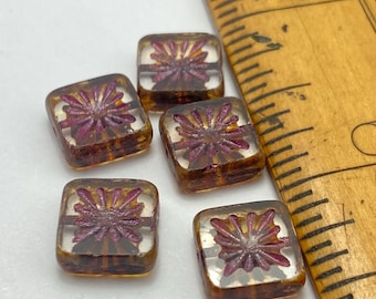 Five Czech glass square beads with plum starburst design on cream, shown against a ruler for scale.