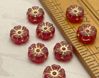 Eight ruby red Czech glass hibiscus flower beads with gold wash details, shown next to a wooden ruler for scale.