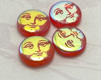 Four Czech tattoo coin beads with red and yellow faces on a plain background showing man in the moon designs.