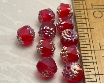 Eight ruby red Czech glass cathedral beads with copper finish, shown next to a wooden ruler for scale