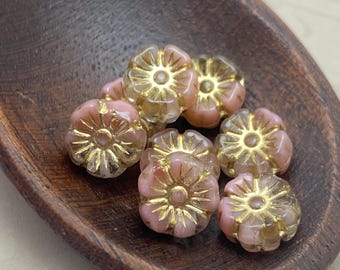 Eight baby pink and gold Czech glass hibiscus flower beads arranged in a wooden bowl.