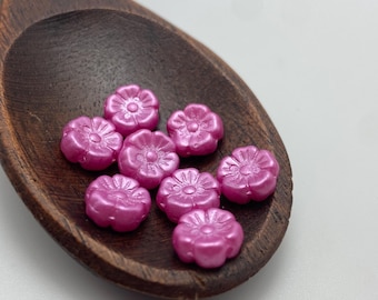 Eight fuchsia pink Czech glass hibiscus flower beads with detailed petals, displayed in a wooden spoon.