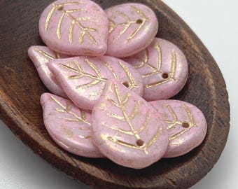 Eight pale pink Czech glass leaf beads with gold wash detail, displayed in a brown wooden oval dish.