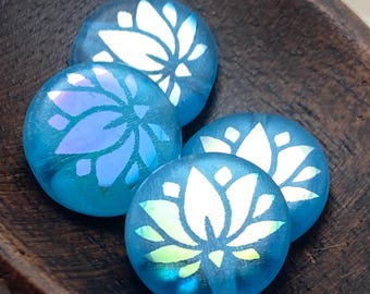 Four blue opal Czech glass coin beads with etched lotus flower designs, arranged on a plain beige background.