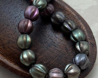 Pewter rainbow Czech glass melon beads in metallic shades of gold, silver, grey, purple and bronze arranged in a loose.
