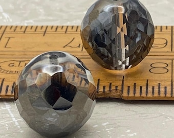 Two large Czech faceted fire polished beads in black silver next to a wooden ruler for scale.