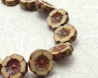 Eight fawn and burgundy Czech glass flower beads arranged in a curve on a white textured background.