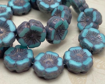 Czech table cut flower beads in turquoise and grey, displayed on a plain pale background, showing their rounded shape.