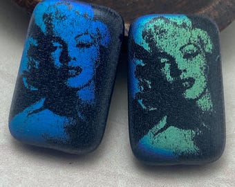Two deep blue laser etched Marilyn Monroe Czech glass beads with contrasting colour faces, shown on a plain background.