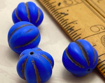 Four matte indigo blue Czech glass melon beads with brown wash detail, shown next to a wooden ruler for scale.