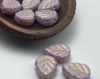 Czech glass hibiscus flower beads in pinky lilac with gold wash detail, shown in a wooden bowl and on a white surface.