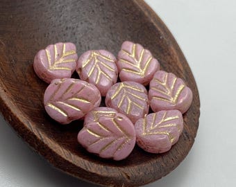 Ten pale pink Czech mint leaf beads with gold wash detail sit in a dark wooden dish on a light background.