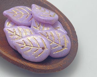 Five pale lilac Czech glass leaf beads with gold wash detail, displayed in a wooden bowl.