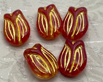 Five red Czech tulip flower beads with yellow gold wash detailing, shown on a light textured background.