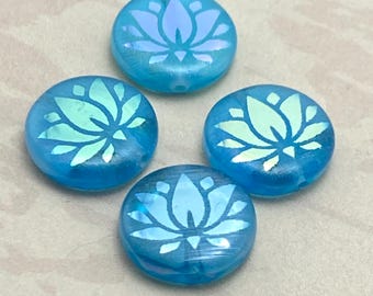 Four blue opal Czech glass coin beads with etched lotus flower designs, arranged on a plain beige background.