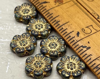 Six black Czech glass anemone flower beads with gold wash detail shown next to a wooden ruler for scale.